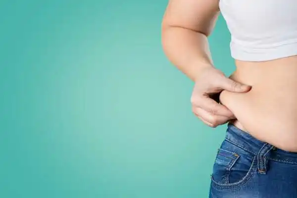 Image of woman pinching her love handles to show weight gain Buckinghamshire