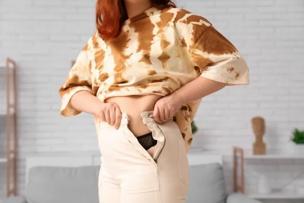 Image of woman trying to do her trousers up after pregnancy weight gain Buckinghamshire